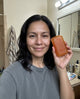 Customer holding the aki persimmon bar in her bathroom
